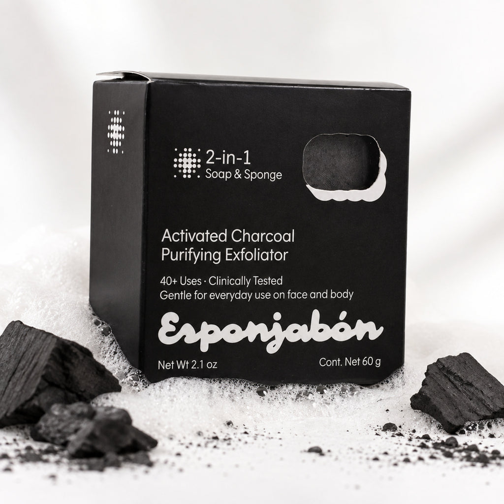 A black rectangular box of Esponjabén Activated Charcoal Purifying Exfoliator, surrounded by loose charcoal pieces and white powder on a white background.