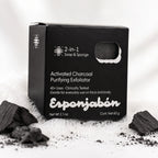 A black rectangular box of Esponjabén Activated Charcoal Purifying Exfoliator, surrounded by loose charcoal pieces and white powder on a white background.