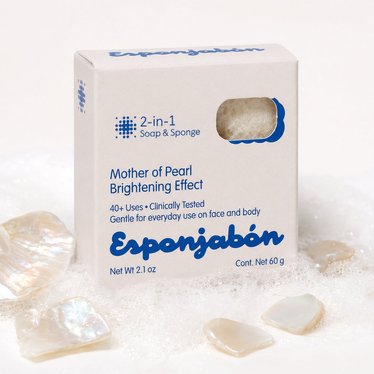 A white box of Esponjabón Mother of Pearl Brightening Effect soap and sponge, surrounded by iridescent mother-of-pearl stones and white powder on a clean white background.